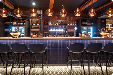 A bar with a long counter and a few stools - Leckerman Law, LLC