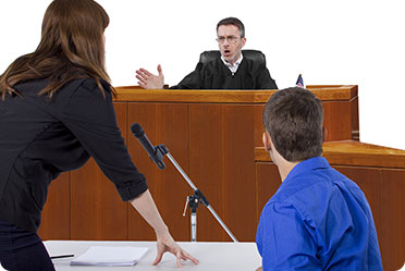 A woman converses with a judge in a courtroom - Leckerman Law, LLC