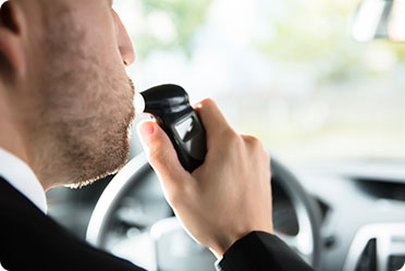 A man with alcohol testing machine in his mouth - Leckerman Law, LLC