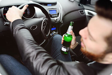 A man dangerously holds a beer bottle while driving - Leckerman Law, LLC