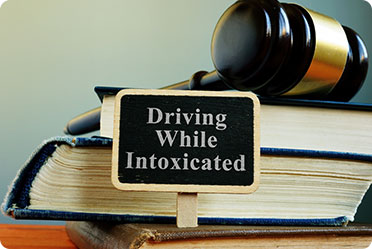 A sign of driving while intoxicated and a gavel on books - Leckerman Law, LLC