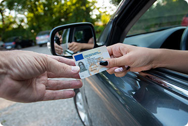 A person handing a driver's license to another person - Leckerman Law, LLC
