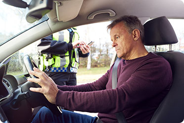 A man in the driver's seat of a car with a police officer standing behind him - Leckerman Law, LLC