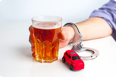 A man handcuffed and holding a glass of alcohol - Leckerman Law, LLC