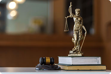 A statue of a lawyer holding a gavel, placed on top of a stack of books - Leckerman Law, LLC