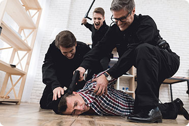 Three guards restraining a man on the floor - Leckerman Law, LLC