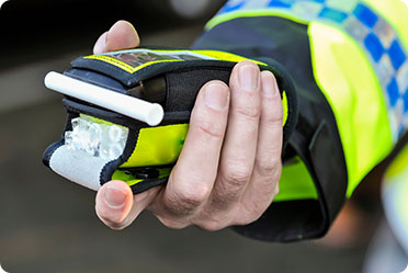 A policeman holding a breathing testing machine - Leckerman Law, LLC