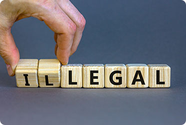 A person holding a wooden block with the word illegal written on it - Leckerman Law, LLC