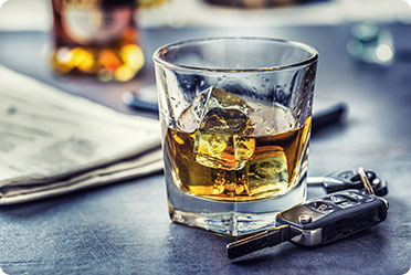 A glass of whiskey and a car key on a table - Leckerman Law, LLC