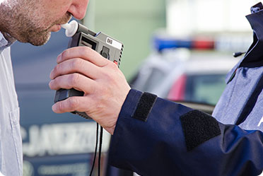 A man holding an electronic device to a police officer for identification purposes - Leckerman Law, LLC