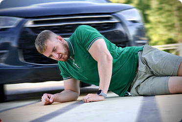 A man lying on the ground next to a car - Leckerman Law, LLC