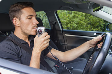 A man in a car with sobriety testing machine - Leckerman Law, LLC