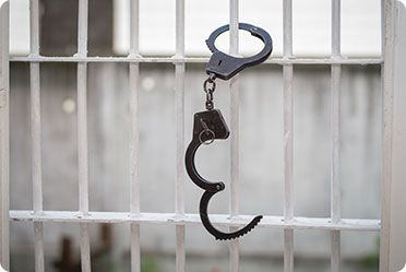 A metal handcuff attached to a jail cell - Leckerman Law, LLC