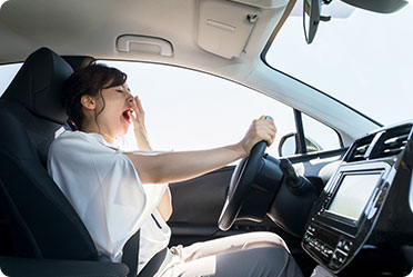 A tired woman driving her car, yawning - Leckerman Law, LLC