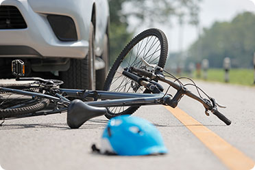 A bicycle lying beside a car on the side of the road - Leckerman Law, LLC