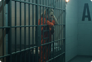 A woman in orange prison clothes stands in a jail cell - Leckerman Law, LLC