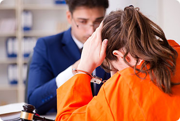 A woman in an orange prison uniform sitting at a desk - Leckerman Law, LLC