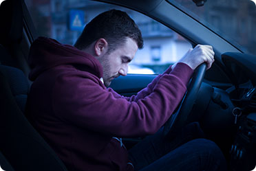 A man sitting in the driver's seat of a car - Leckerman Law, LLC