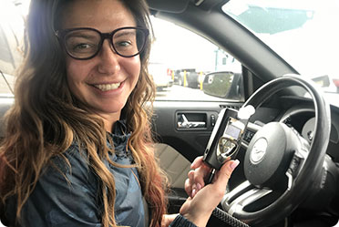 A woman wearing glasses sits in a car - Leckerman Law, LLC