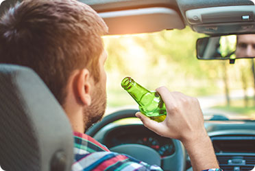 A man enjoying a beer while seated in a car - Leckerman Law, LLC