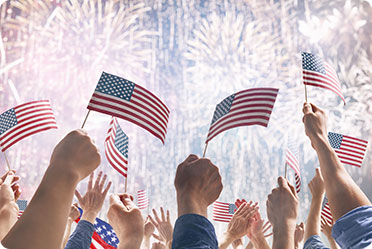 Many people holding American flags in front of fireworks - Leckerman Law, LLC